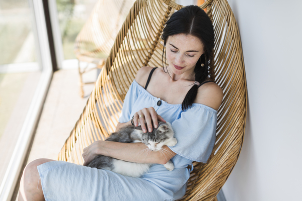 Žena s kočkou v nářučích sedící v závěsném křesle